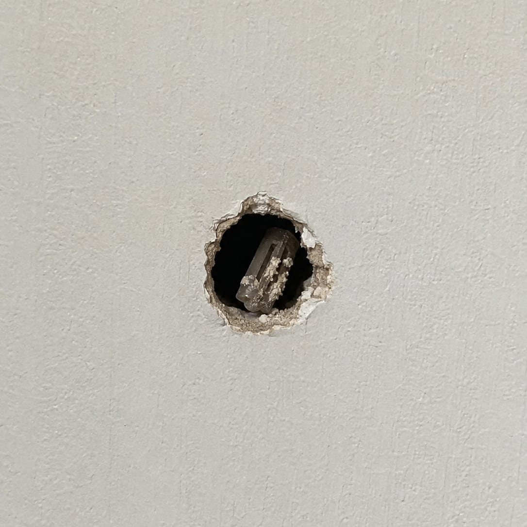 Close view of an anchor hole left in drywall before it is filled