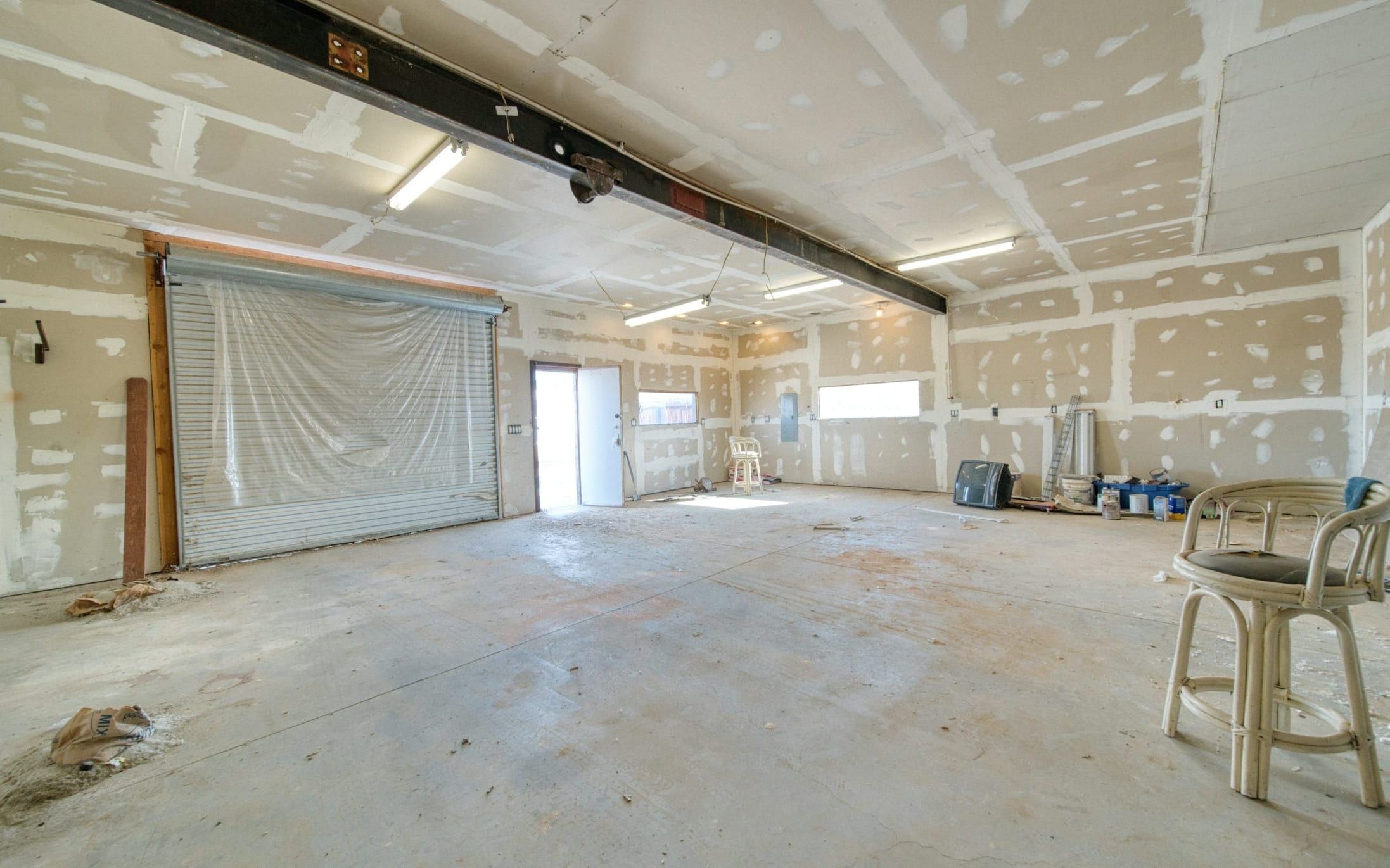 Open room with drywall going up over the framing before finishing begins