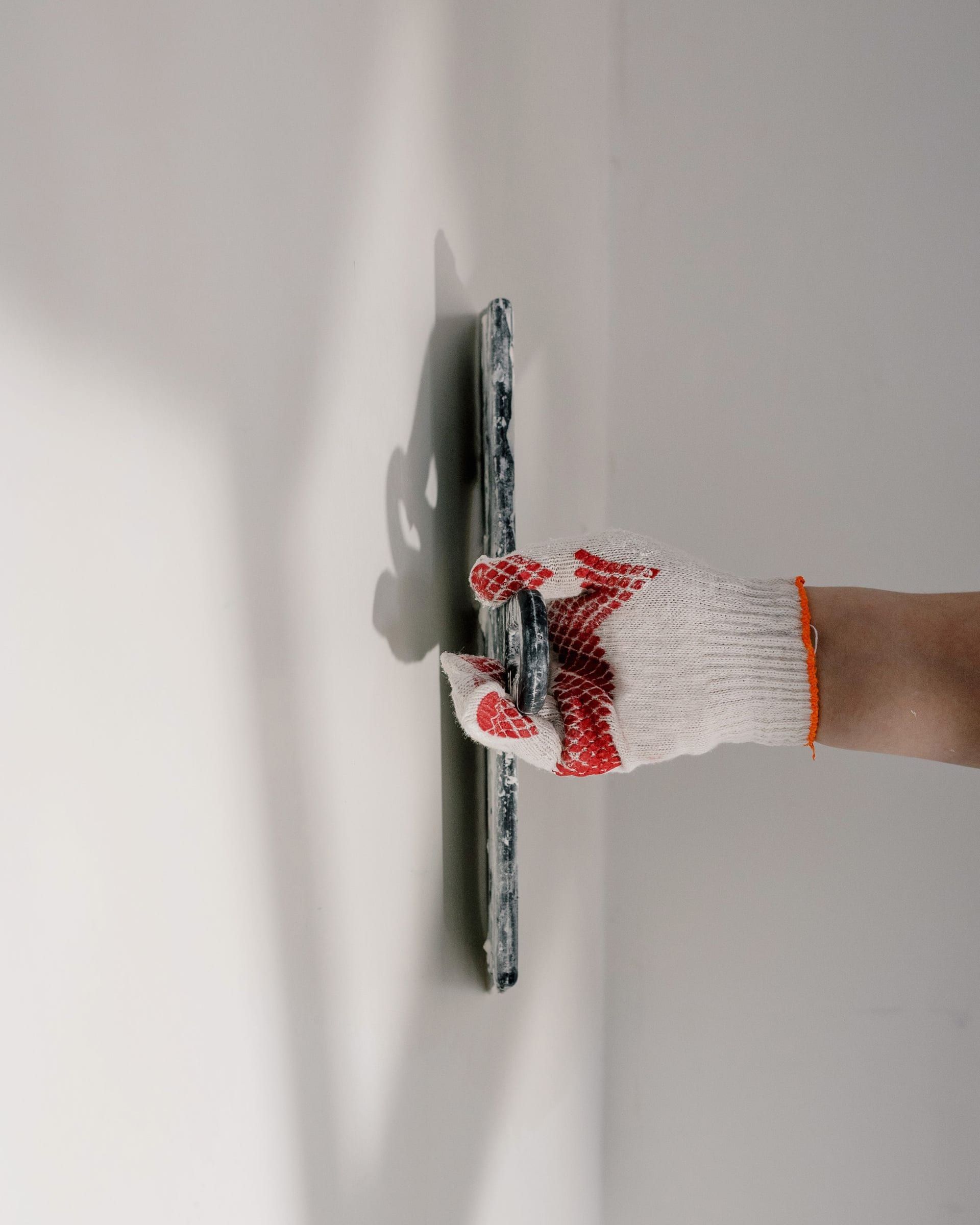 Wide knife drawing joint compound down a wall during a repair