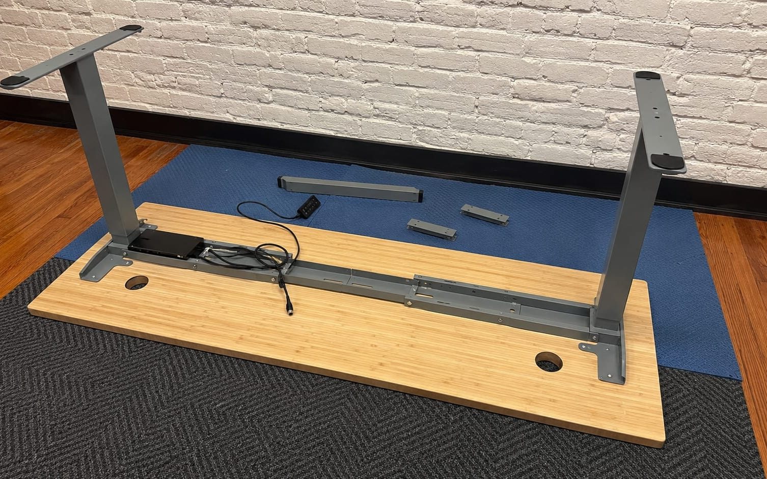 Standing desk top and frame parts laid out on the floor part way through a build