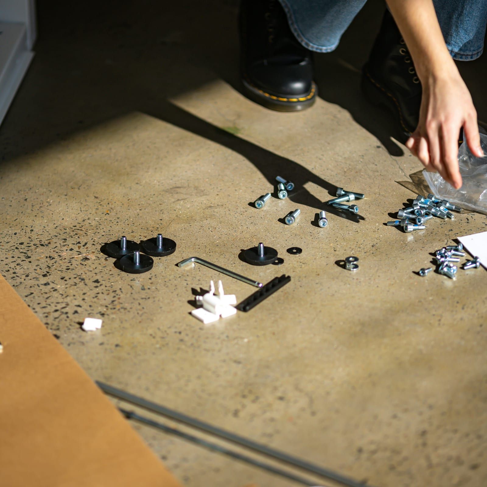 Flat-pack fittings, screws, and an allen key laid out on the floor before assembly starts