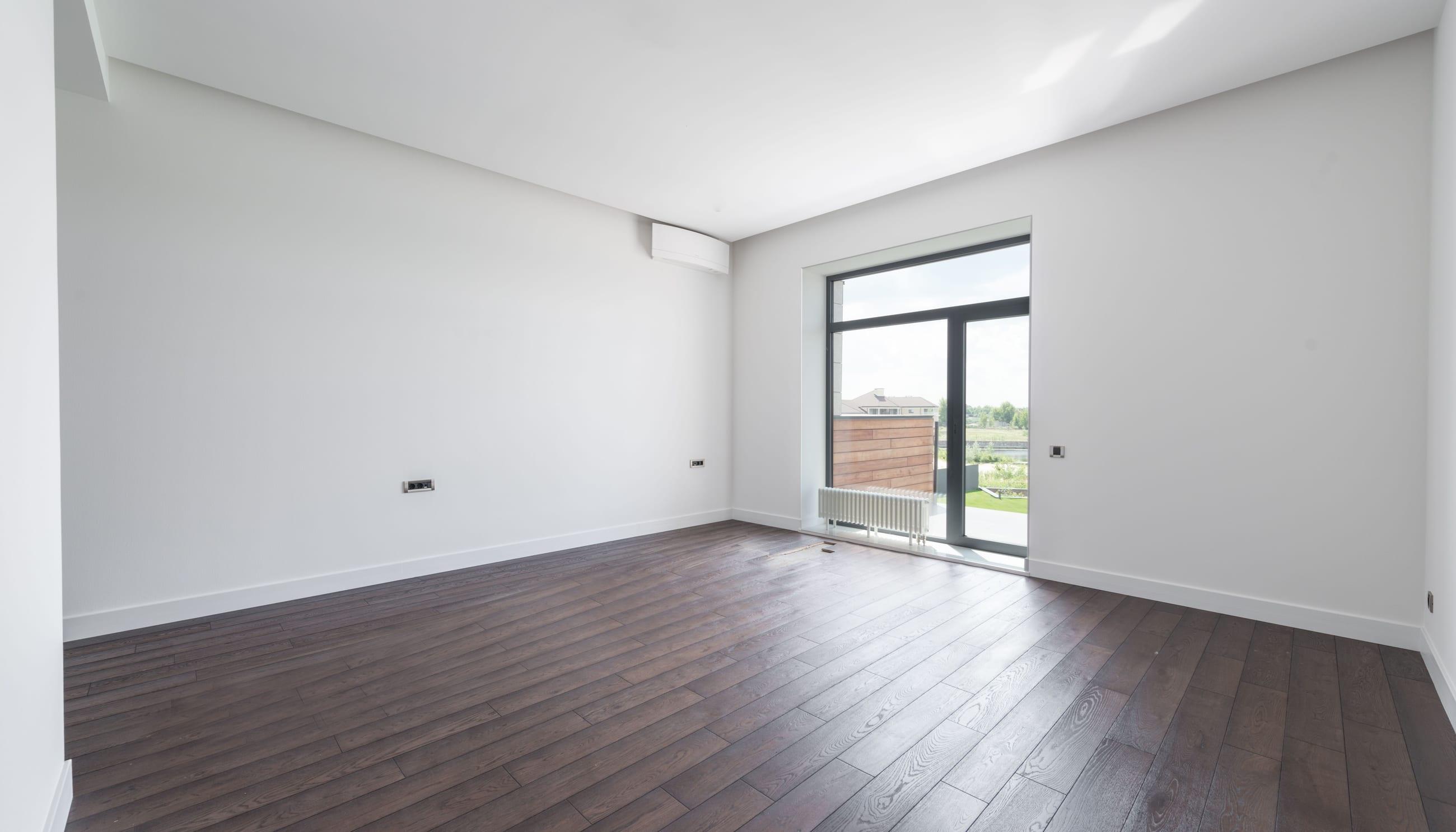 Freshly painted empty interior with clean white walls and dark wood floors
