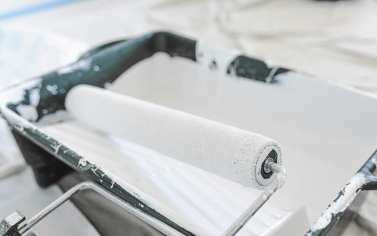 Paint roller loaded in a tray during wall touch-up prep