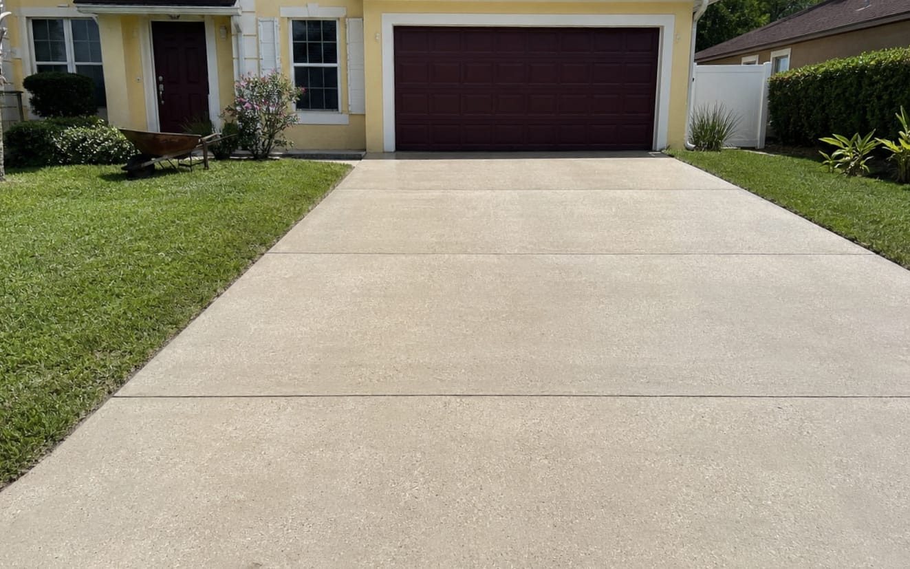 Finished driveway washed back to clean concrete in front of a garage
