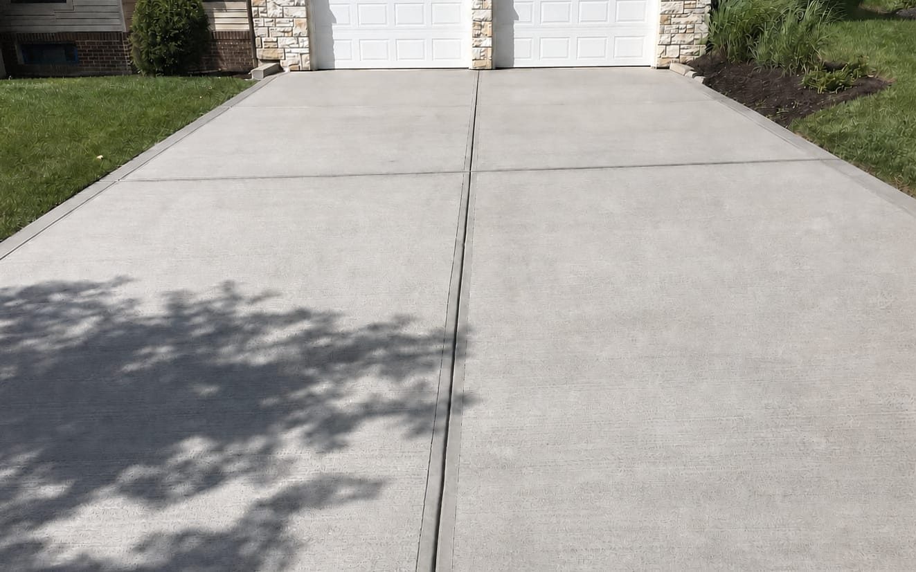 Concrete driveway washed clean end to end in front of a two-car garage