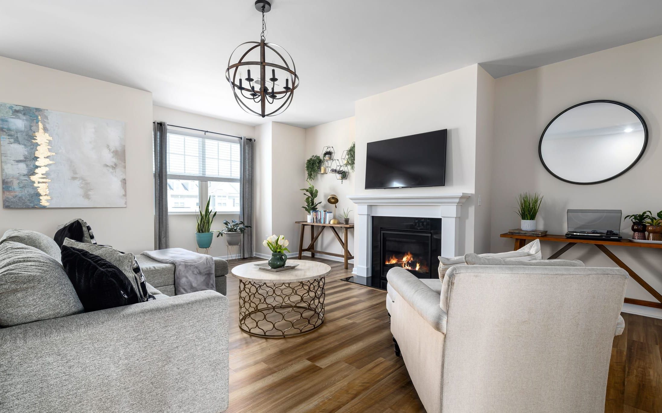 Living room with a TV mounted above the fireplace and a round mirror on the wall