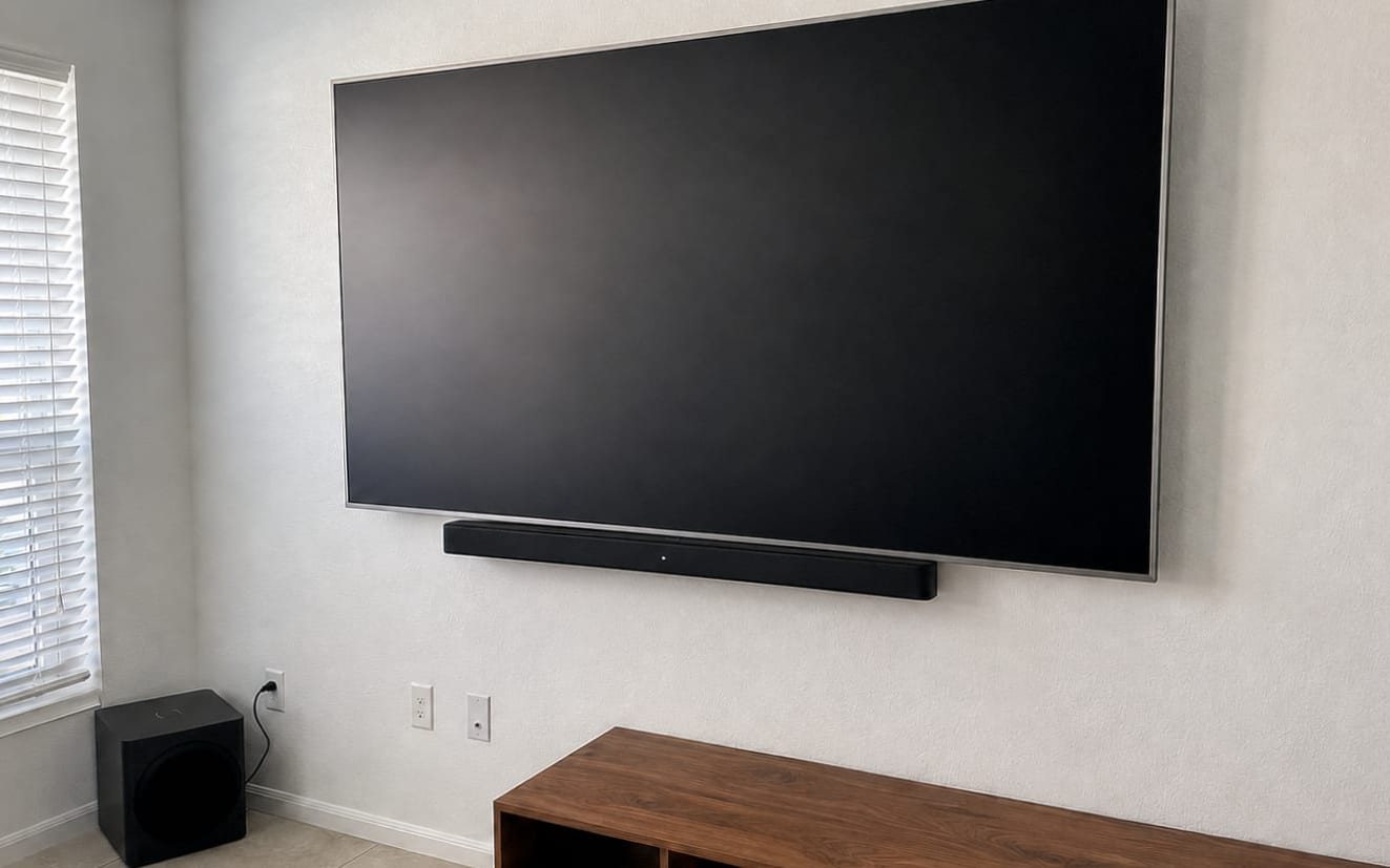 Large flat-screen TV with a soundbar mounted beneath it and the cords hidden inside the wall